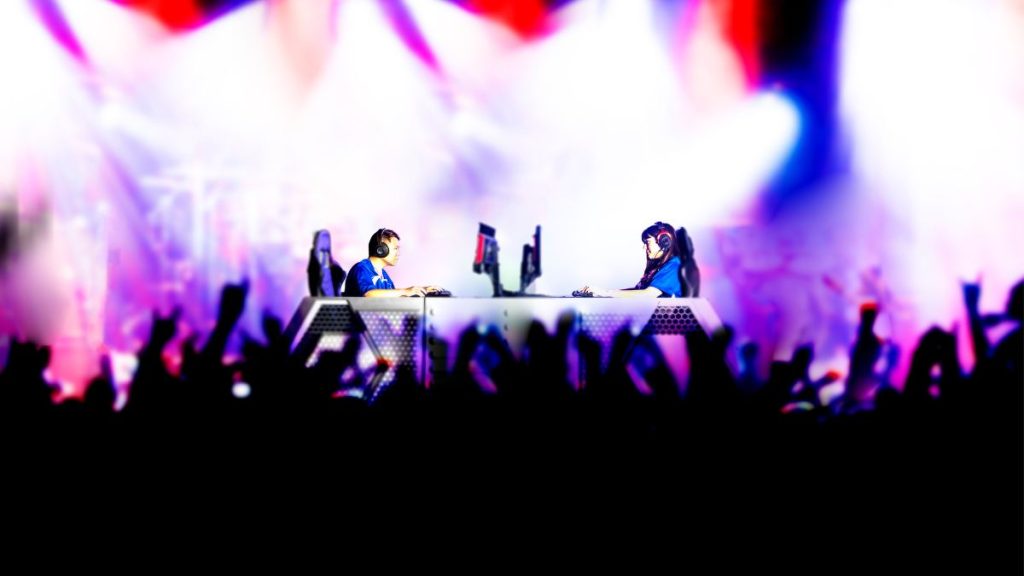 An image of two esports professionals competing on stage in front of a crowd of people